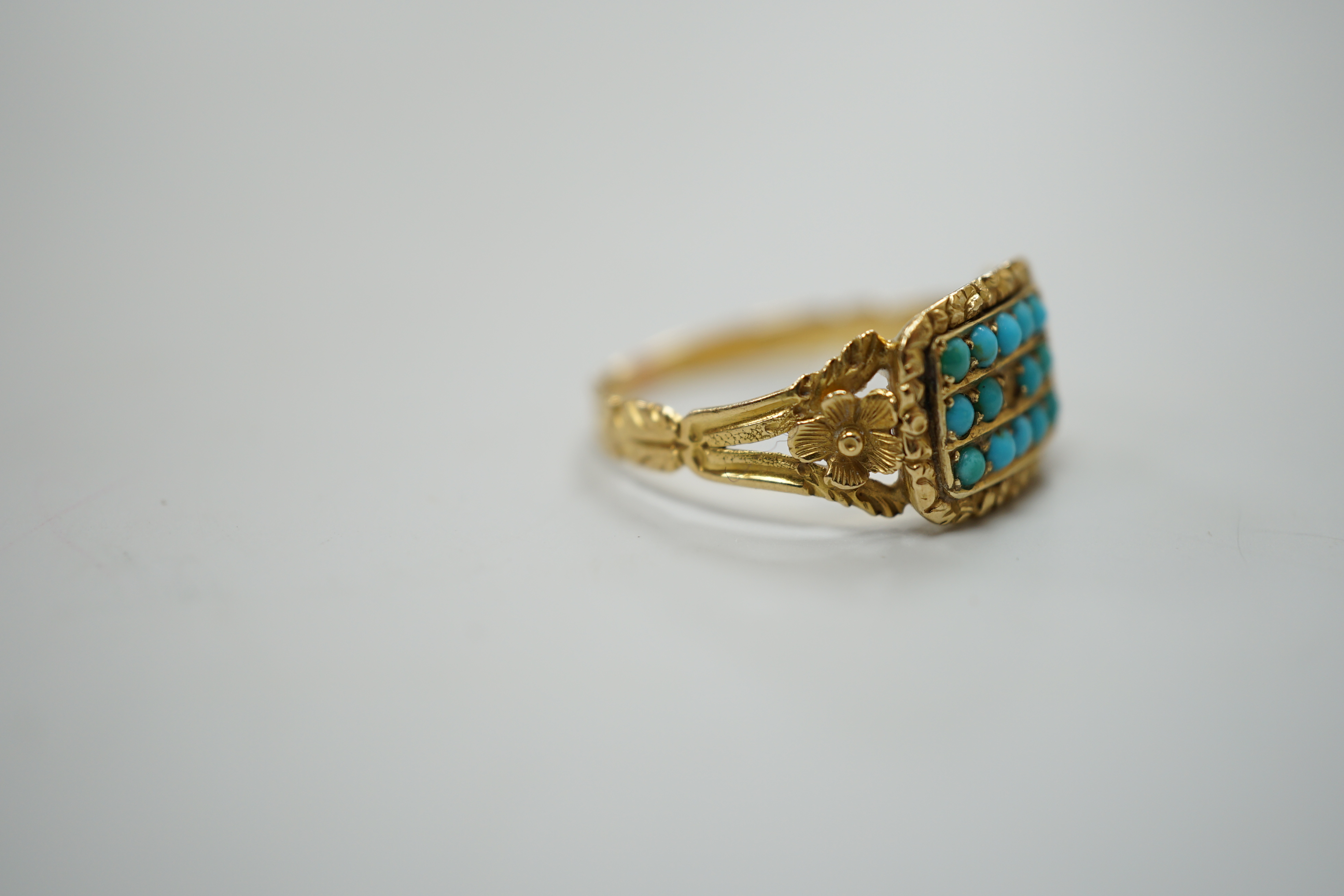 A Victorian gold dress ring, set with three rows of small turquoise flanked by floral carved shoulders, lacks one stone, size O, gross 2.5 grams